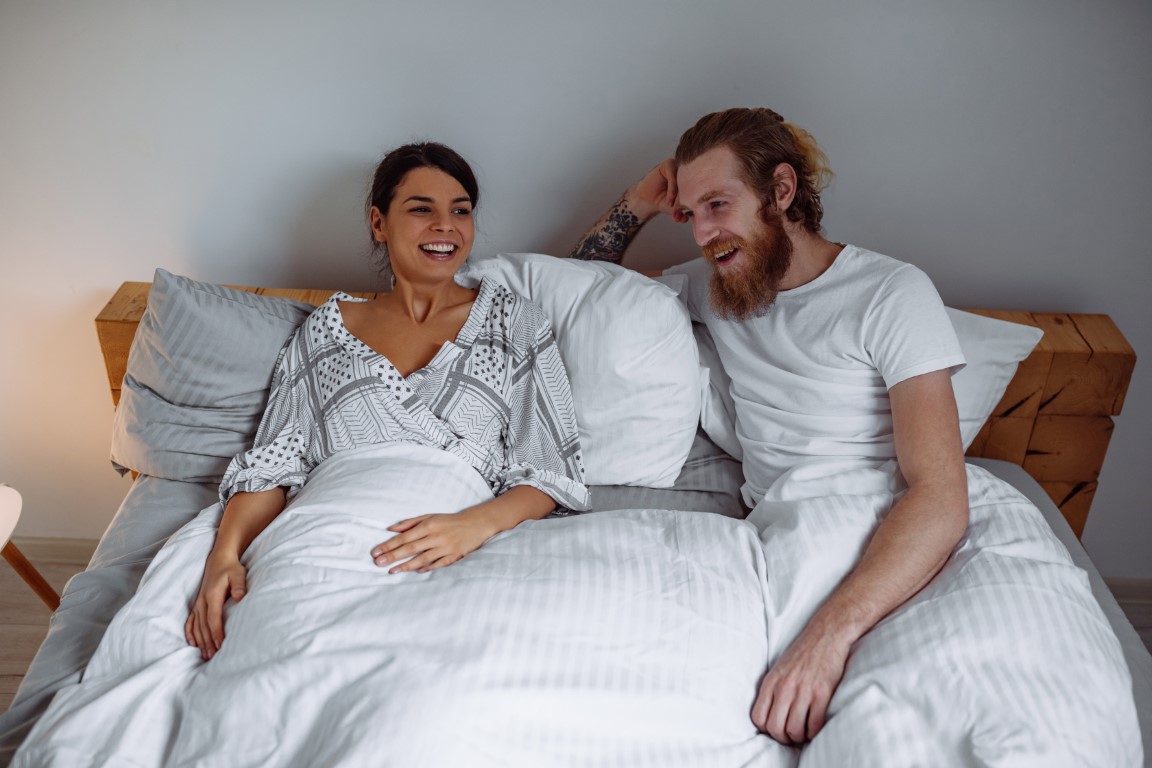 Smejúci sa pár v posteli po použití krúžku na penis